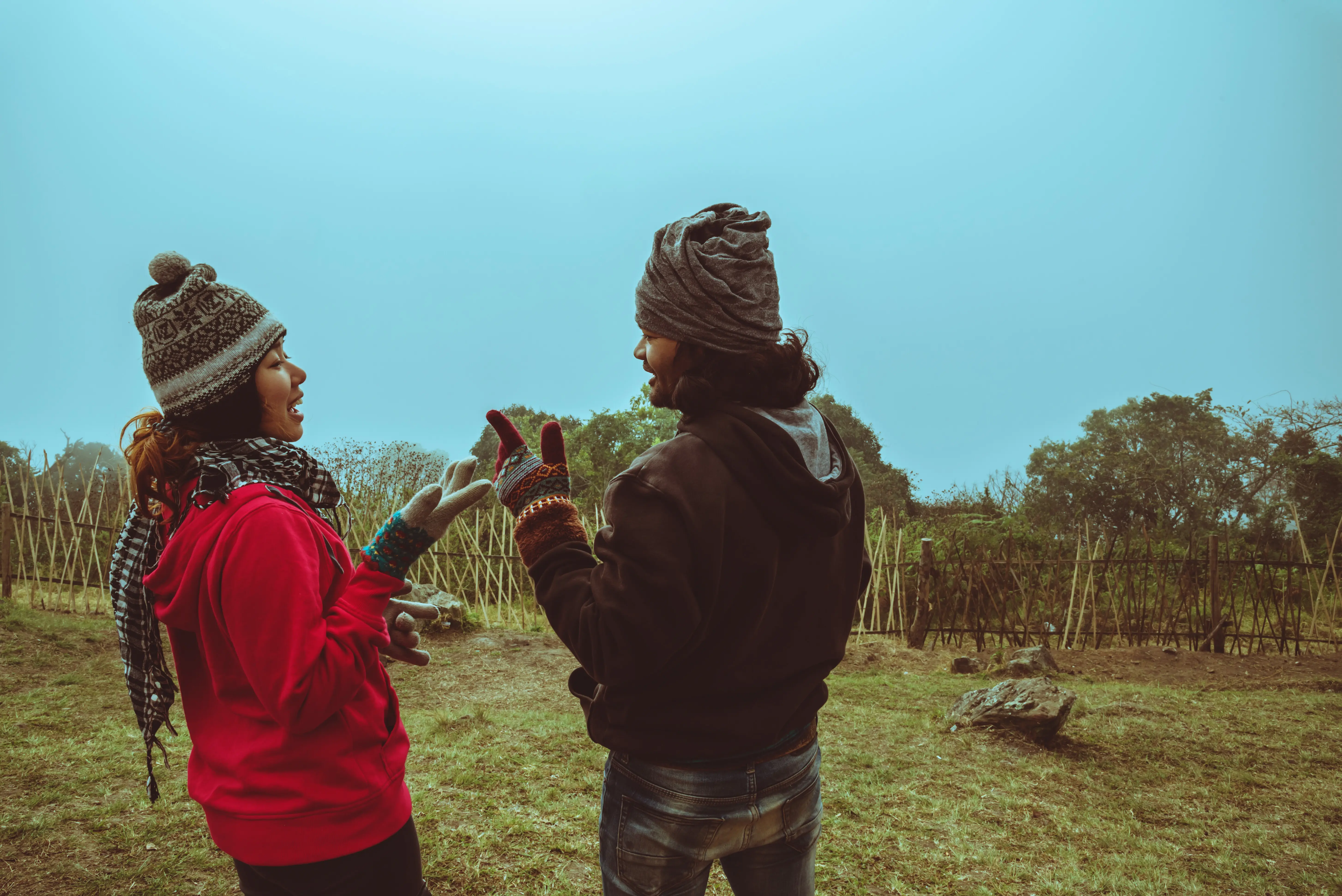Blick von hinten auf einen Mann und eine Frau, die auf einem Feld stehen.