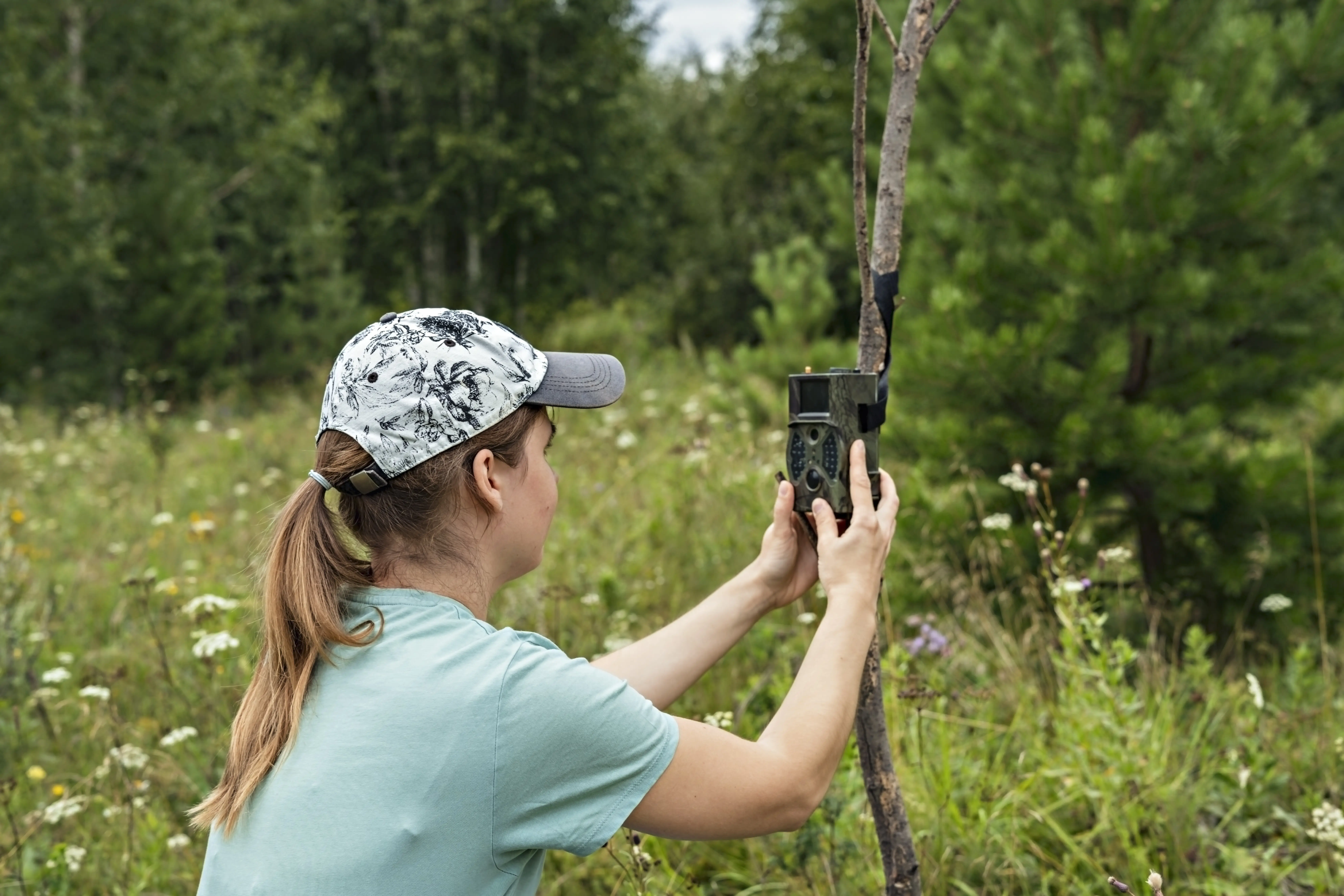 Eine Frau, die im Wald eine Kamera hält.